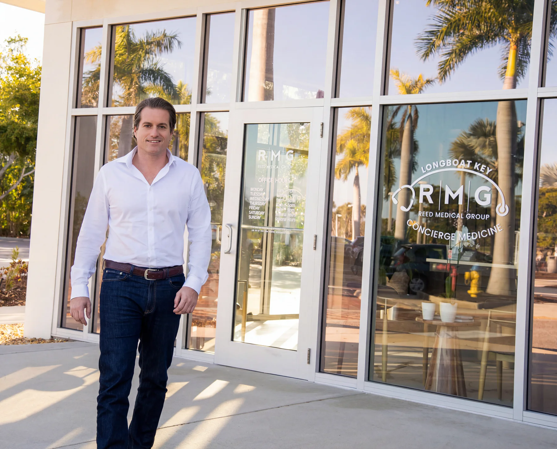 Dr. Reed standing outside Reed Medical Group’s Longboat Key office with the practice identity visible on the windows.