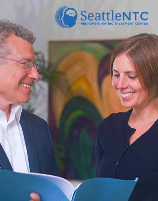 Two SeattleNTC clinicians reviewing documents beneath the neuropsychiatric treatment center logo.