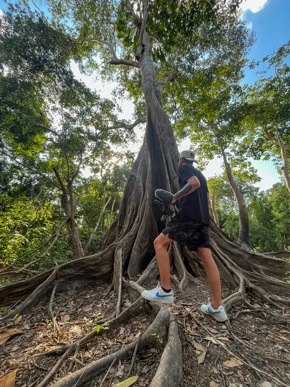 Mac Hoover carrying a production camera through a tropical forest.